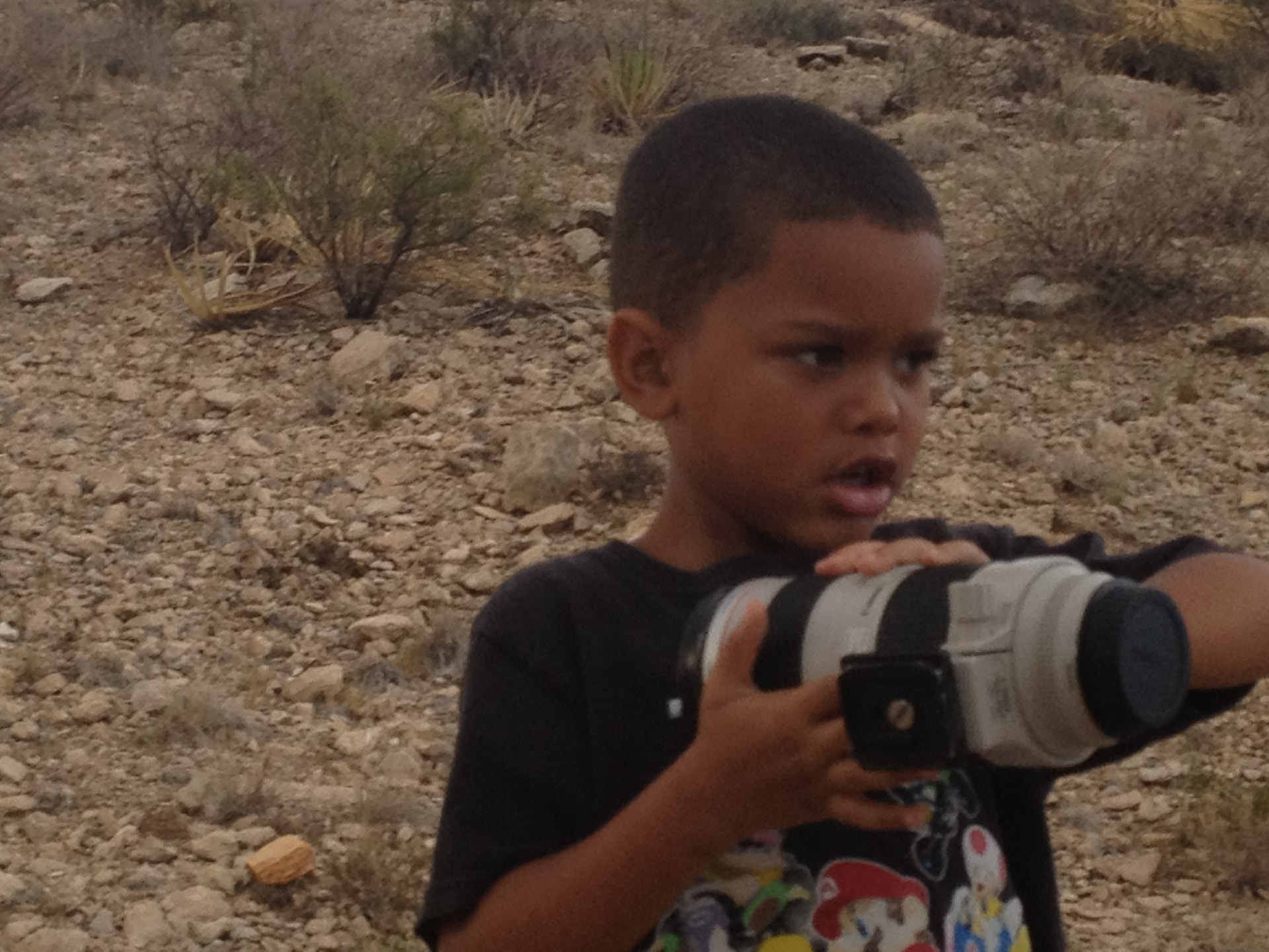 A young Roby Davis holding a telephoto lens in the desert